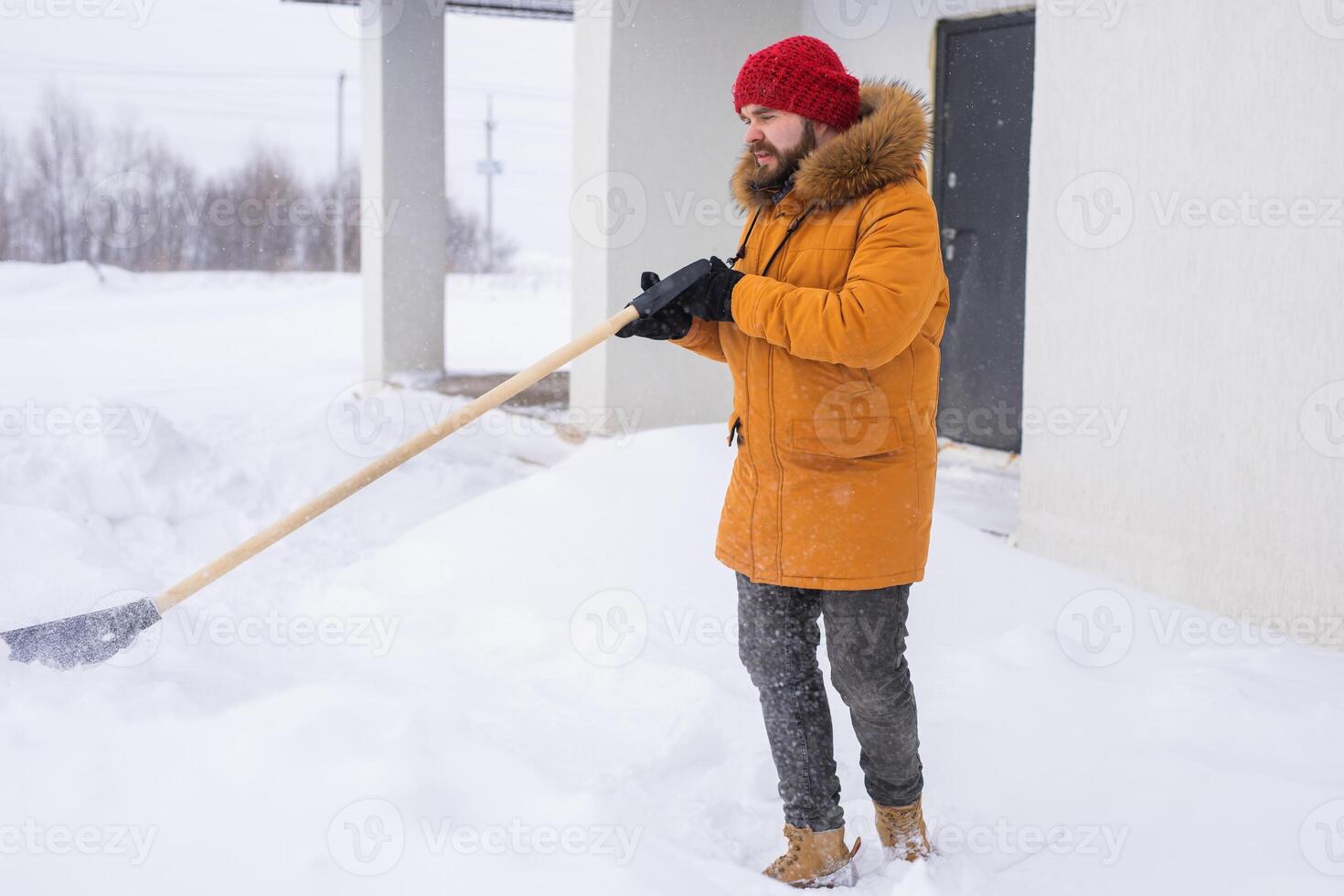 Man removing snow and ice from the sidewalk in front of house. Winter season photo