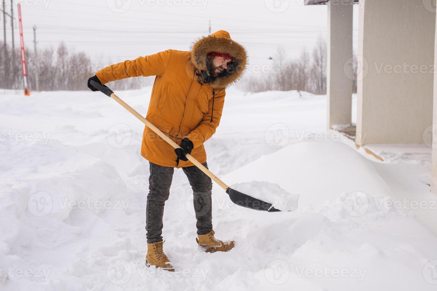 Man is clearing the snow near house and on staircases hovelling at the winter season. Winter storm and season specific photo