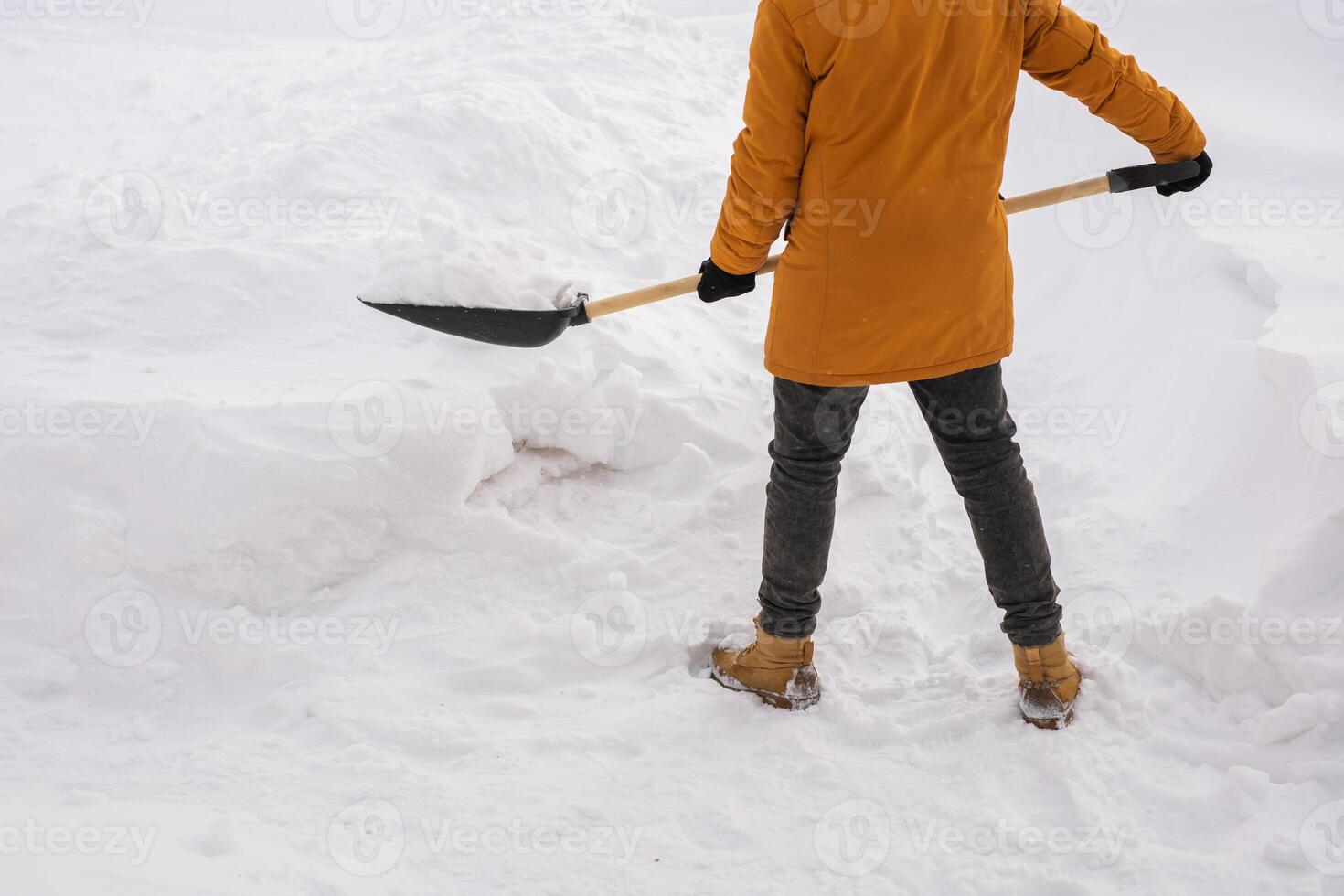 Close up man cleaning snow from sidewalk and using snow shovel. Winter season photo