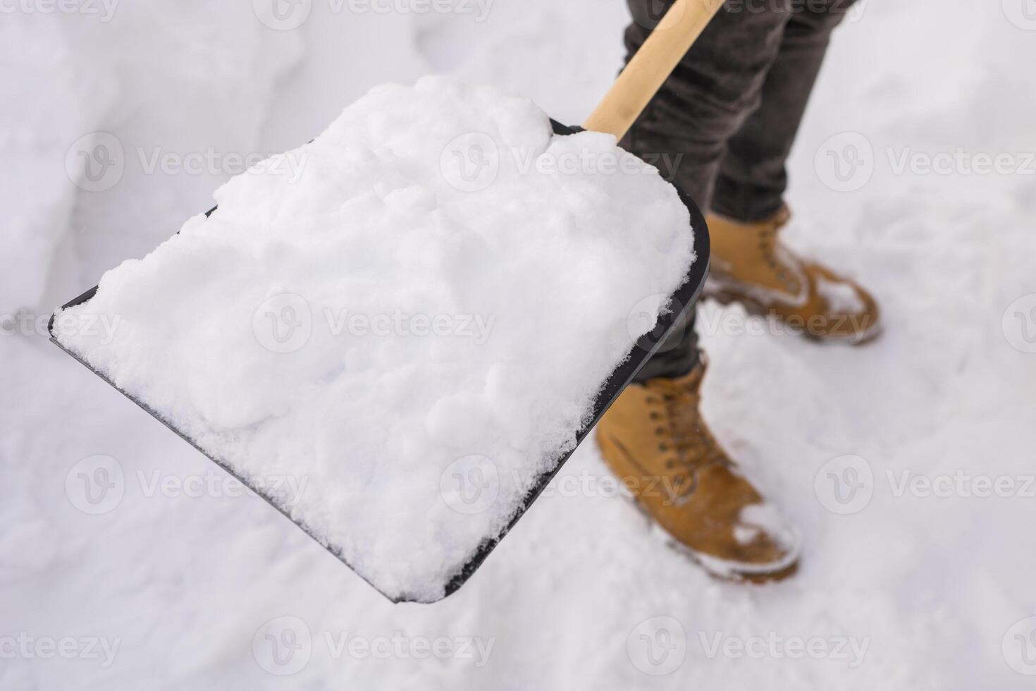 Close-up Man removing snow and ice from the sidewalk in front of house. Winter season photo