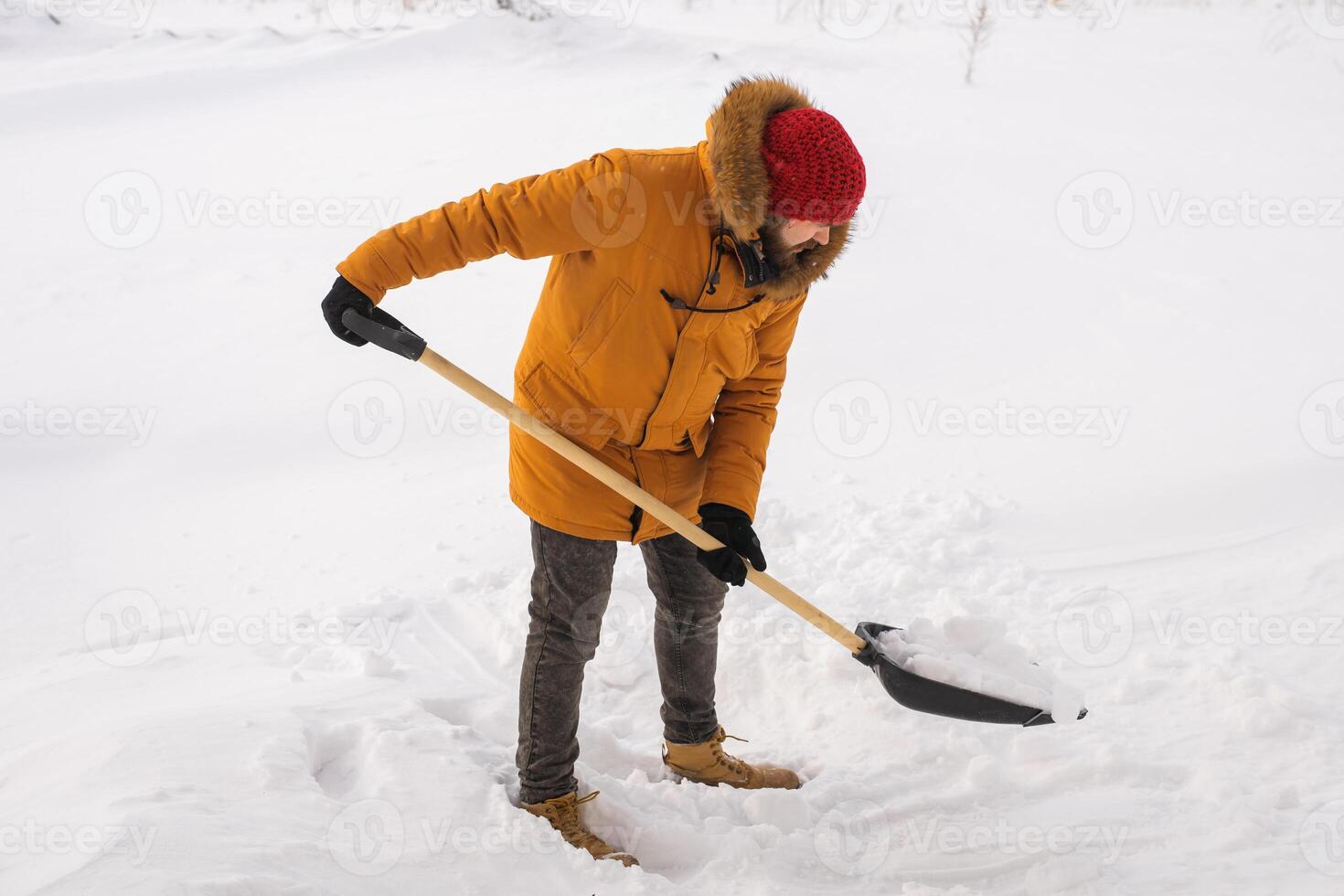 Young man clearing snow in his backyard village house with shovel. Remove snow from the sidewalk. photo
