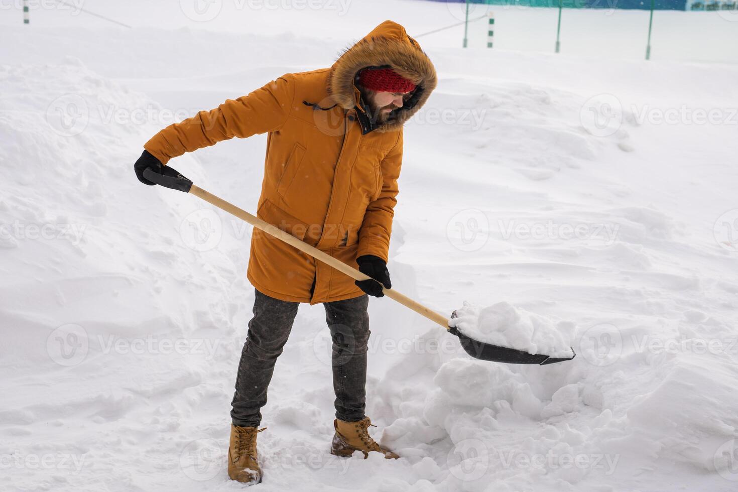 A man cleans and clears the snow in front of the house on frosty day. Cleaning the street from snow on a winter day. Snowfall and severe snowstorm in winter. photo