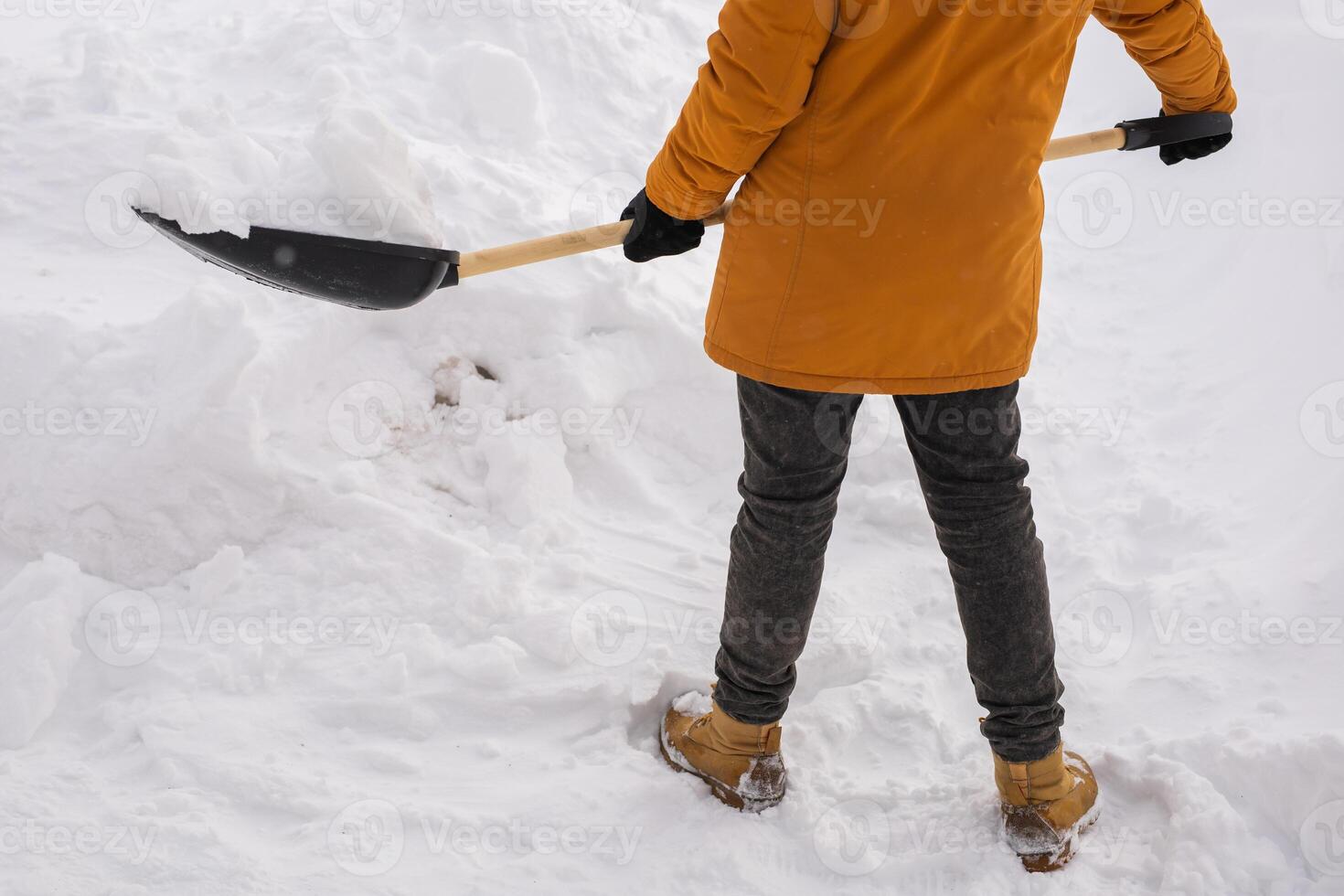 Close-up man is clearing the snow near house and on staircases hovelling at the winter season. Winter storm and season specific photo
