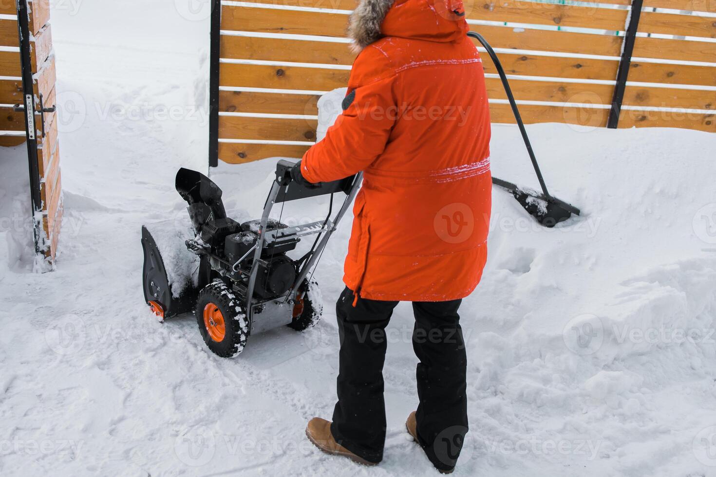 A man clear snow from backyard with snow blower. Winter season and snow blower equipment photo