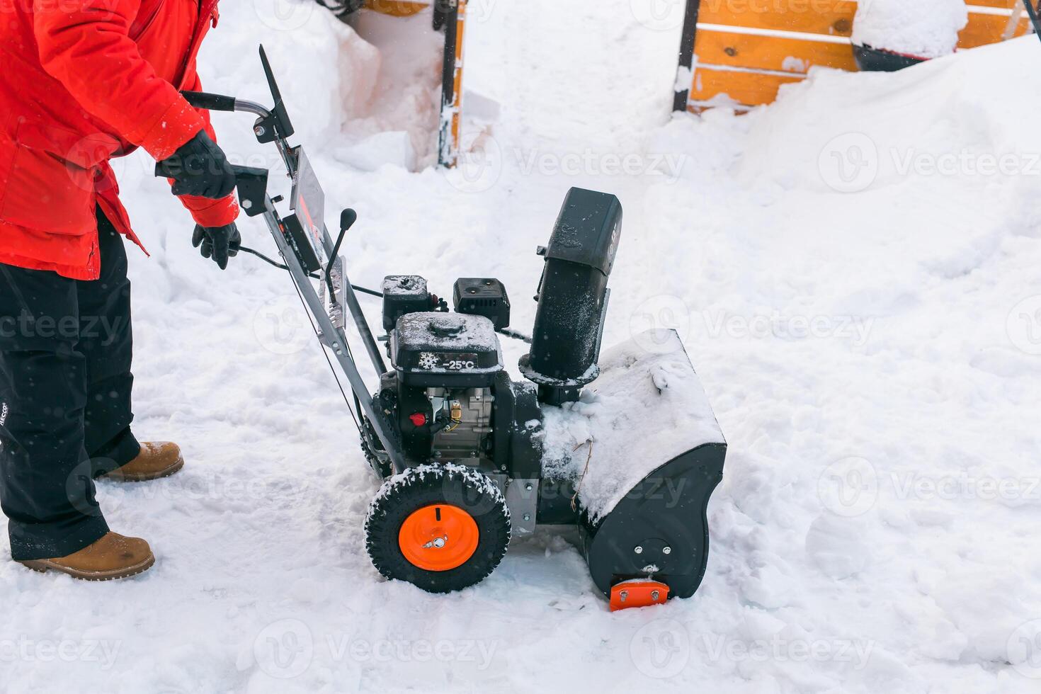Closeup of red snow blower in action. Senior mature man outdoor in front of house using snowblower machine for removing snow on yard. Snow thrower in winter outside home. Young worker guy blowing snow photo