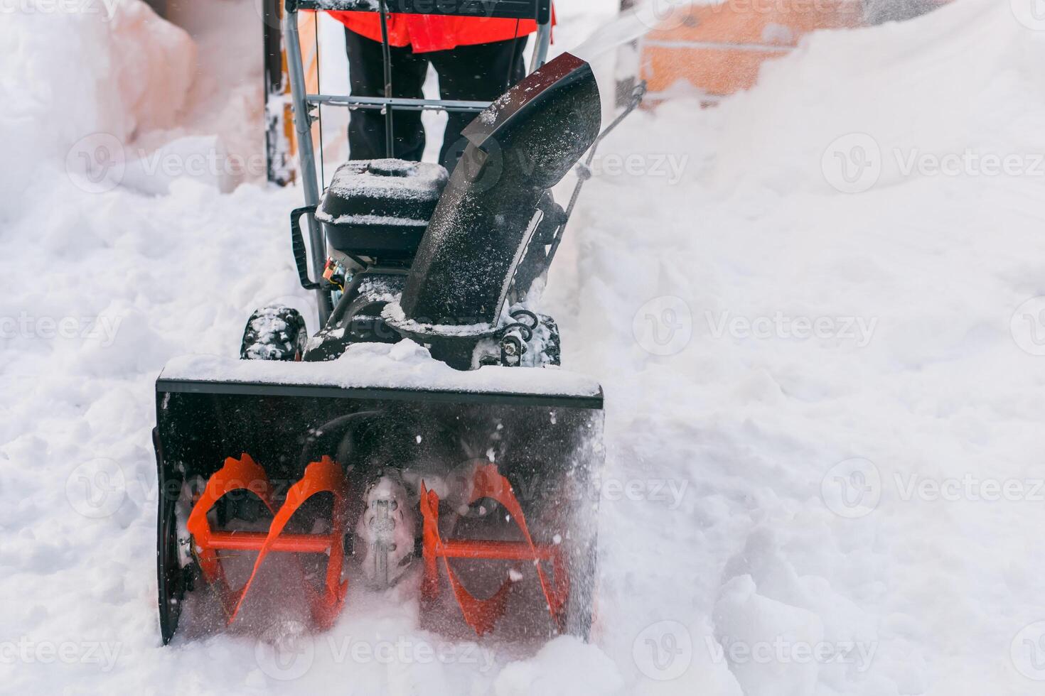 Closeup of red snow blower in action. Senior mature man outdoor in front of house using snowblower machine for removing snow on yard. Snow thrower in winter outside home. Young worker guy blowing snow photo