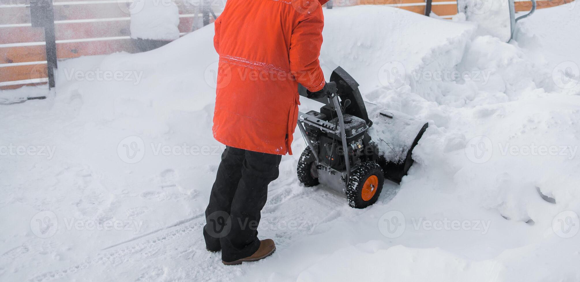 Banner of red snow blower in action. Senior mature man outdoor in front of house using snowblower machine for removing snow on yard. Snow thrower in winter outside home. Young worker guy blowing snow photo