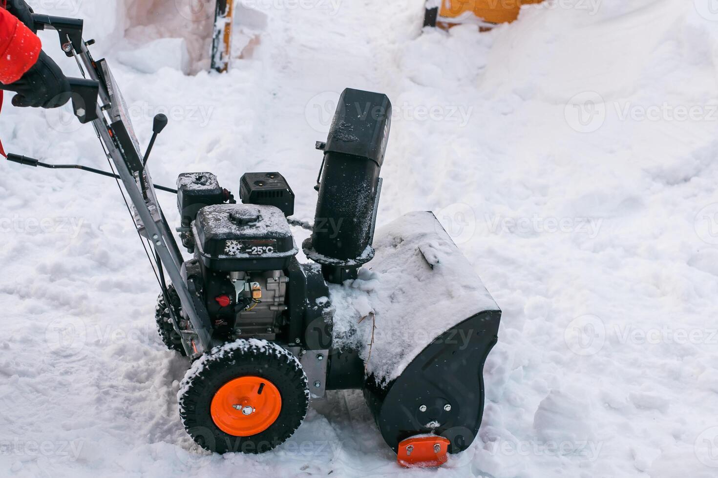 Closeup of red snow blower in action. Senior mature man outdoor in front of house using snowblower machine for removing snow on yard. Snow thrower in winter outside home. Young worker guy blowing snow photo