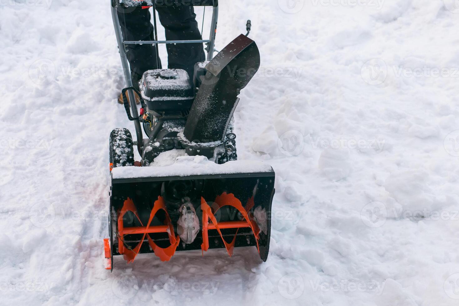 Closeup of red snow blower in action. Senior mature man outdoor in front of house using snowblower machine for removing snow on yard. Snow thrower in winter outside home. Young worker guy blowing snow photo