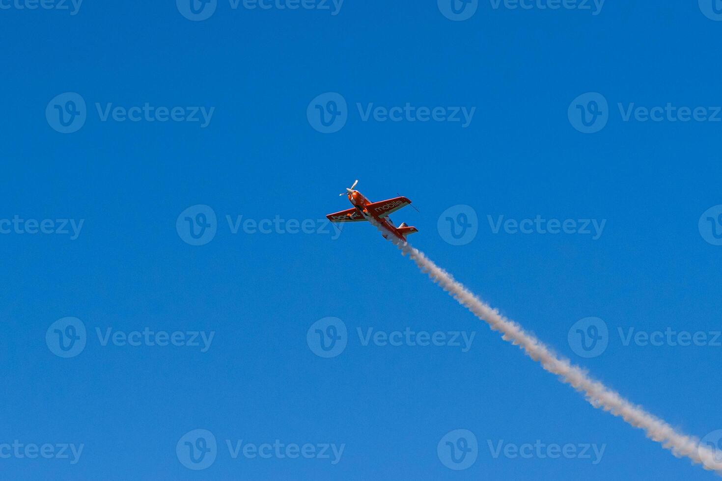 A small plane flying through the sky with smoke trailing behind it photo