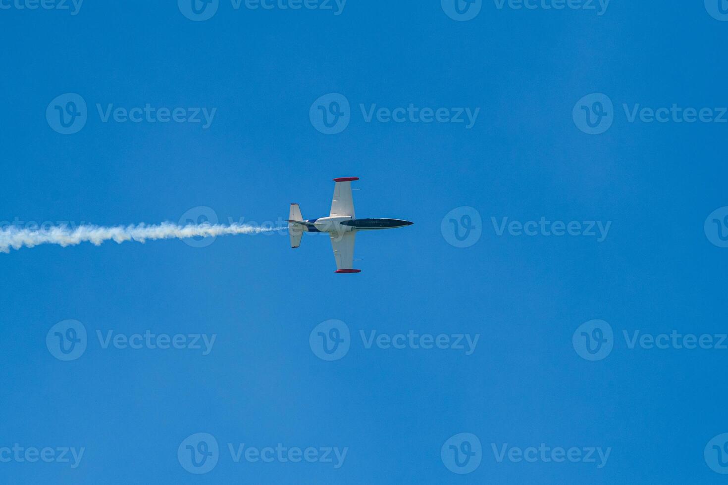 A plane flying in the sky with a white trail photo