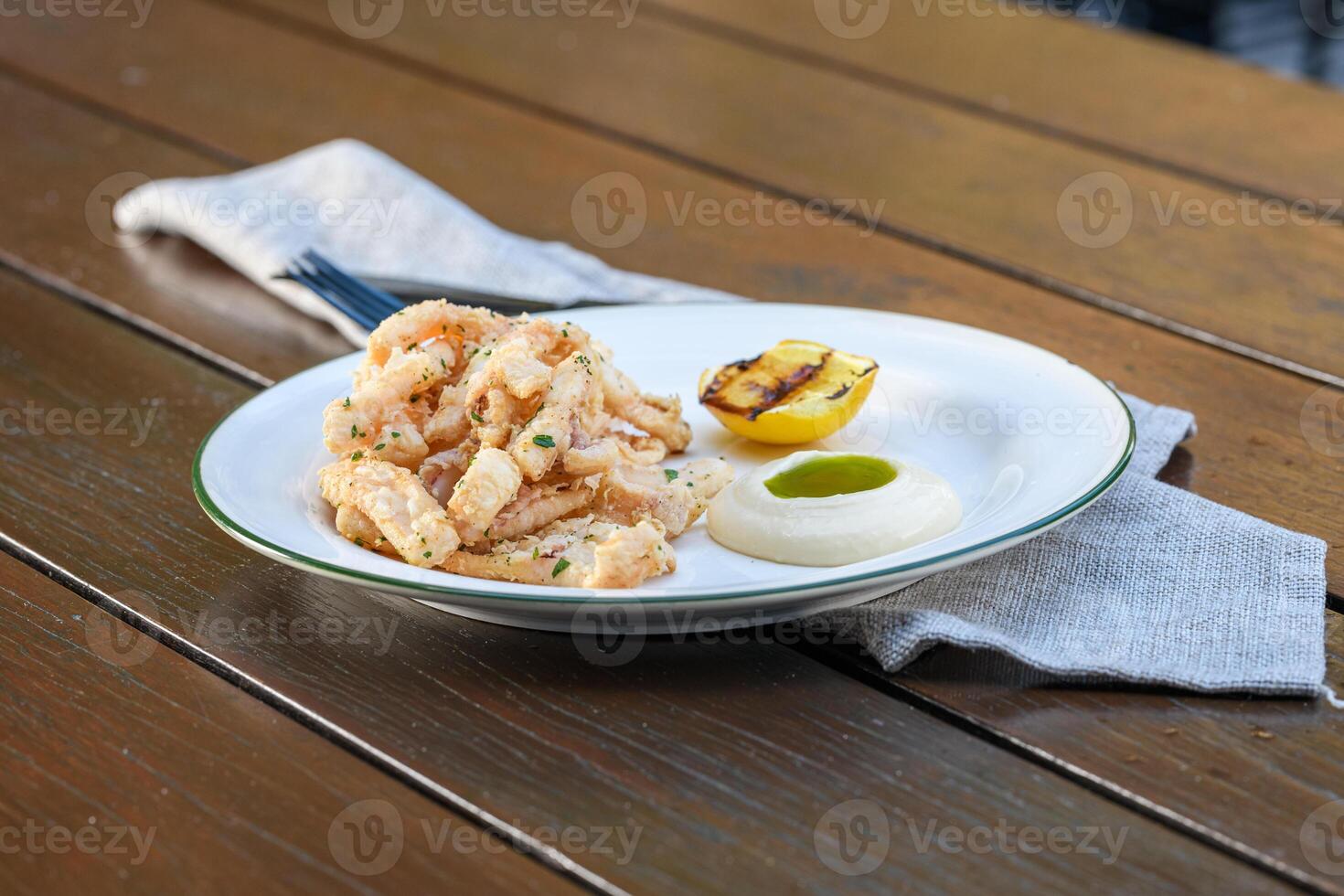 A plate of shrimp and a lemon on a wooden table photo