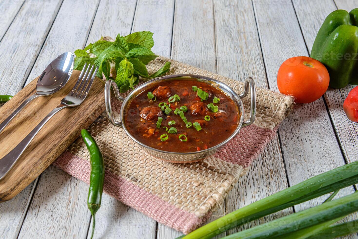 A bowl of chili and vegetables on a table photo