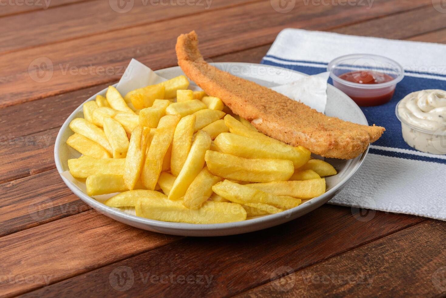 Fish and chips on a plate with a dipping sauce photo