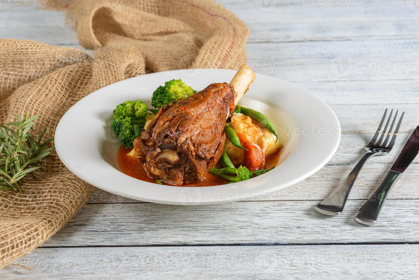 A plate of food with meat and vegetables on a wooden table photo