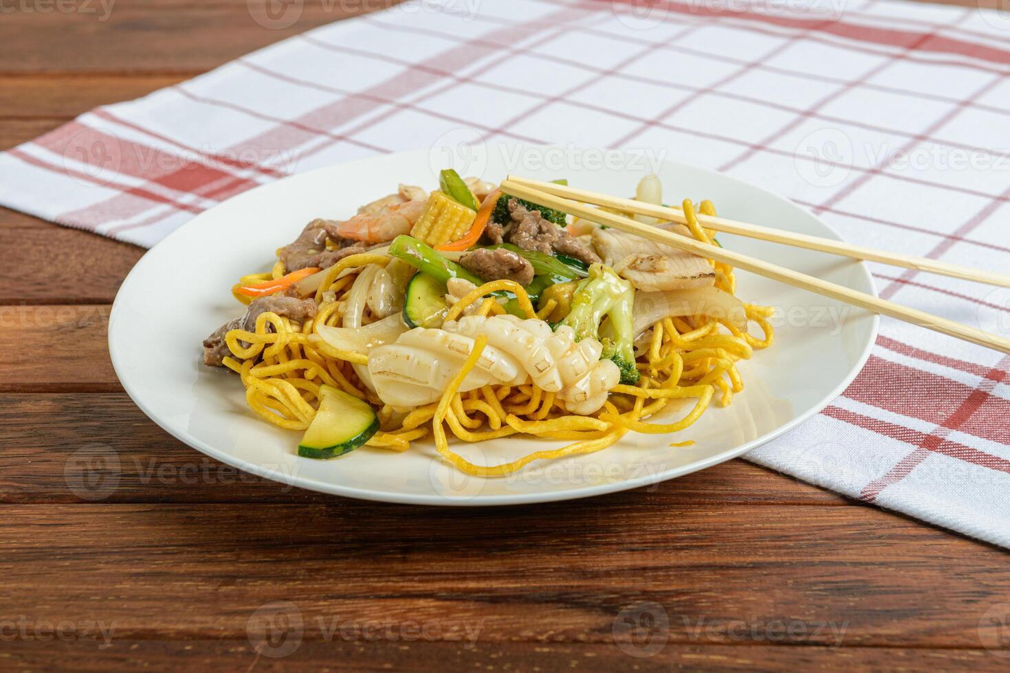 A plate of noodles and vegetables on a table photo