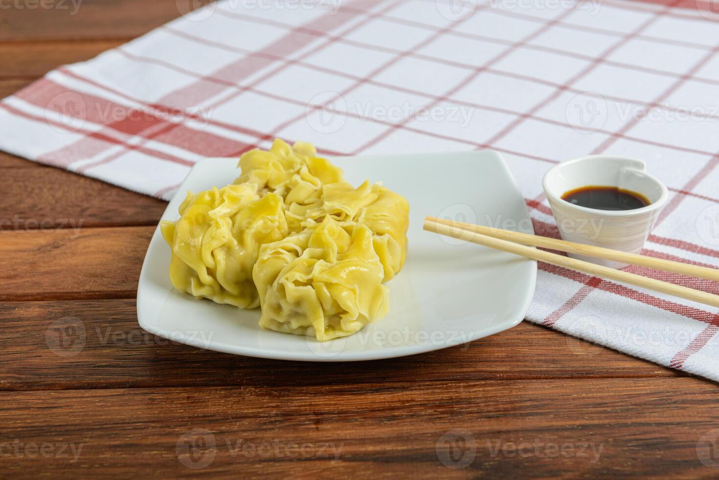 Chinese dumplings with dipping sauce on a white plate photo