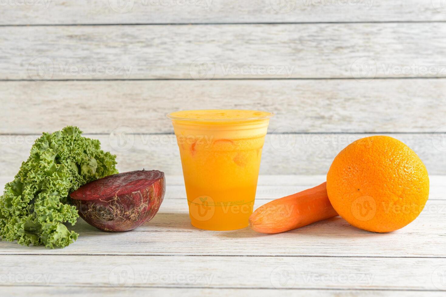 A table with a cup of juice and some vegetables photo