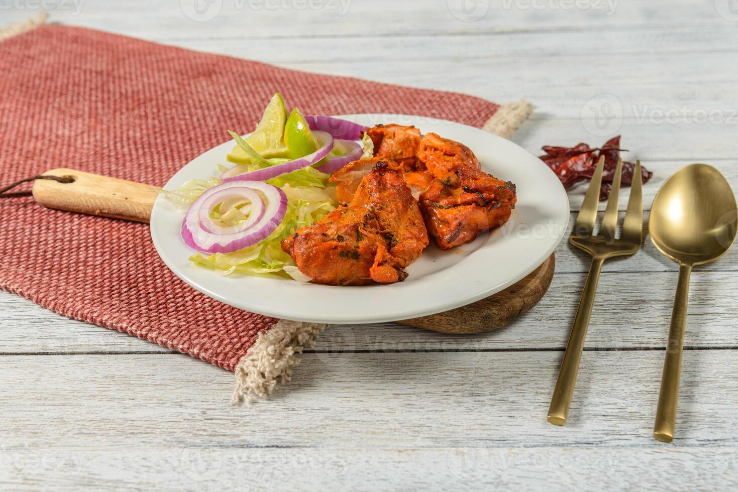 A plate with chicken, onions and salad on a red cloth photo
