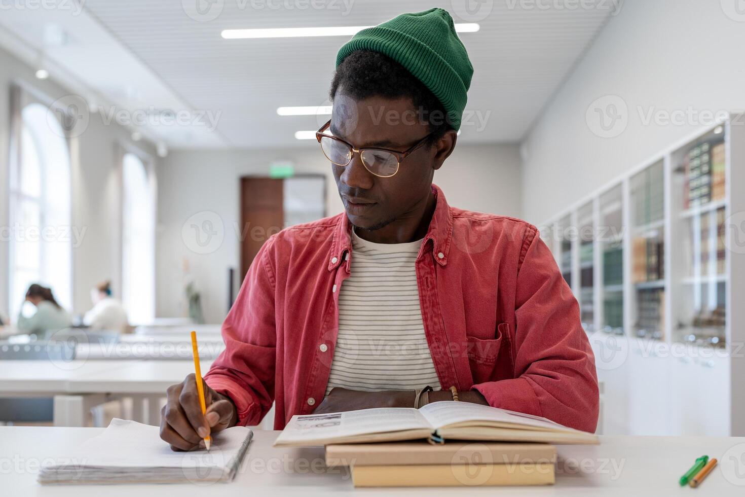Focused african american guy college student sitting at desk with textbooks, studying in library photo