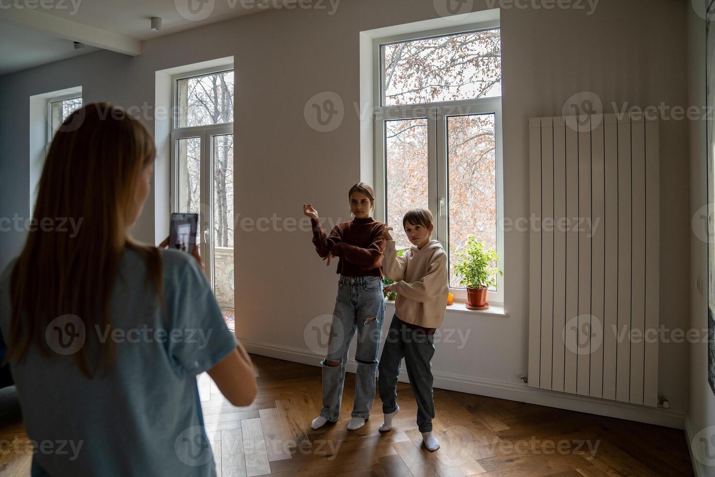 Mother holding smartphone helping kids to record funny dance for social media photo
