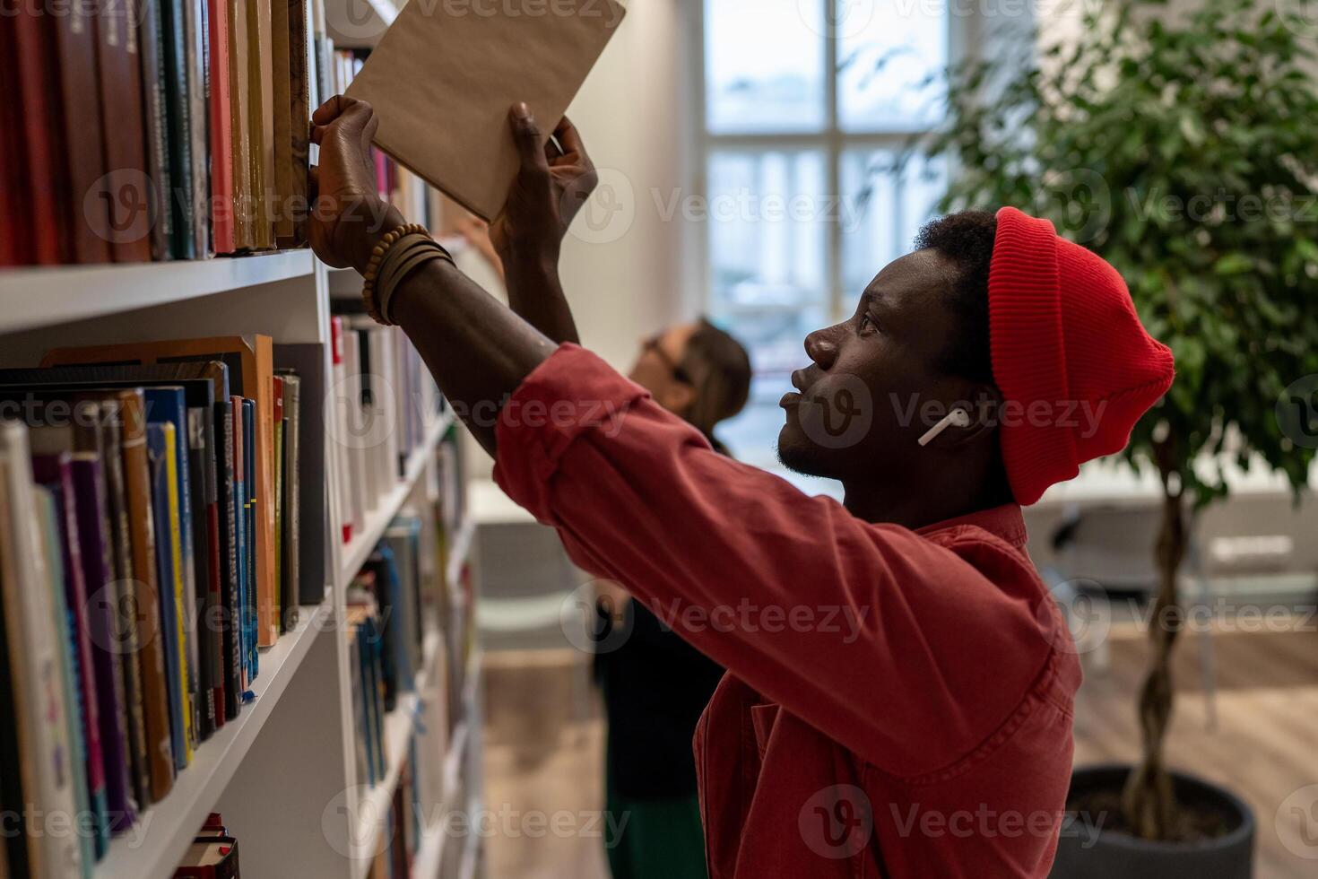 Concentrated African American student man picking books for preparing for exam in university library photo