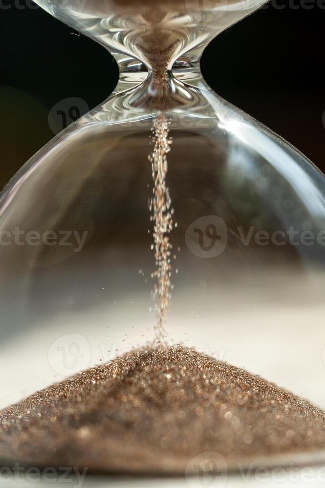 Shiny sand grains running in inverted hourglass lasting certain amount of time as transience of life photo