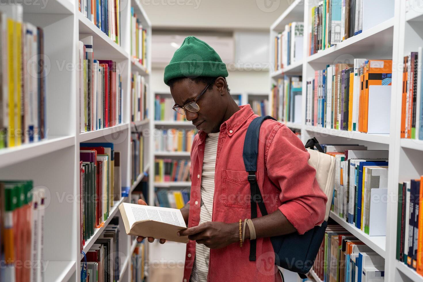 Passionate reader student african american guy choosing research textbooks in university library. photo