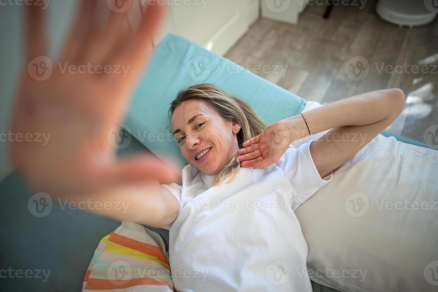 Smiling relaxed woman gently wakes up, stretching to camera. Sleep schedule, happy morning balance photo