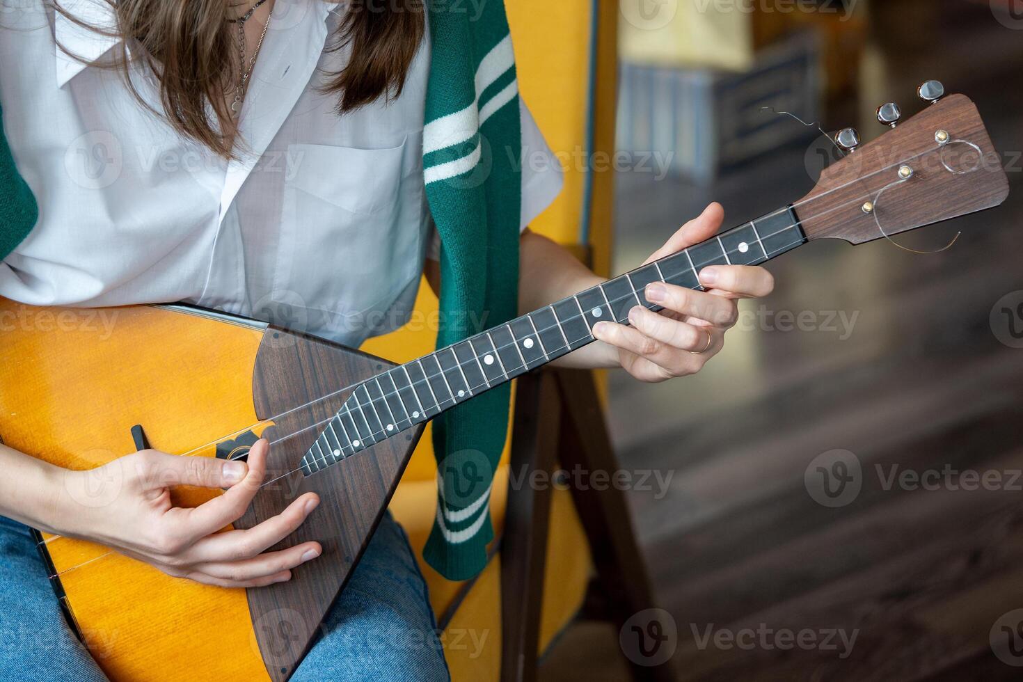 Girl playing on Russian balalaika at home, closeup view on hands and strings photo