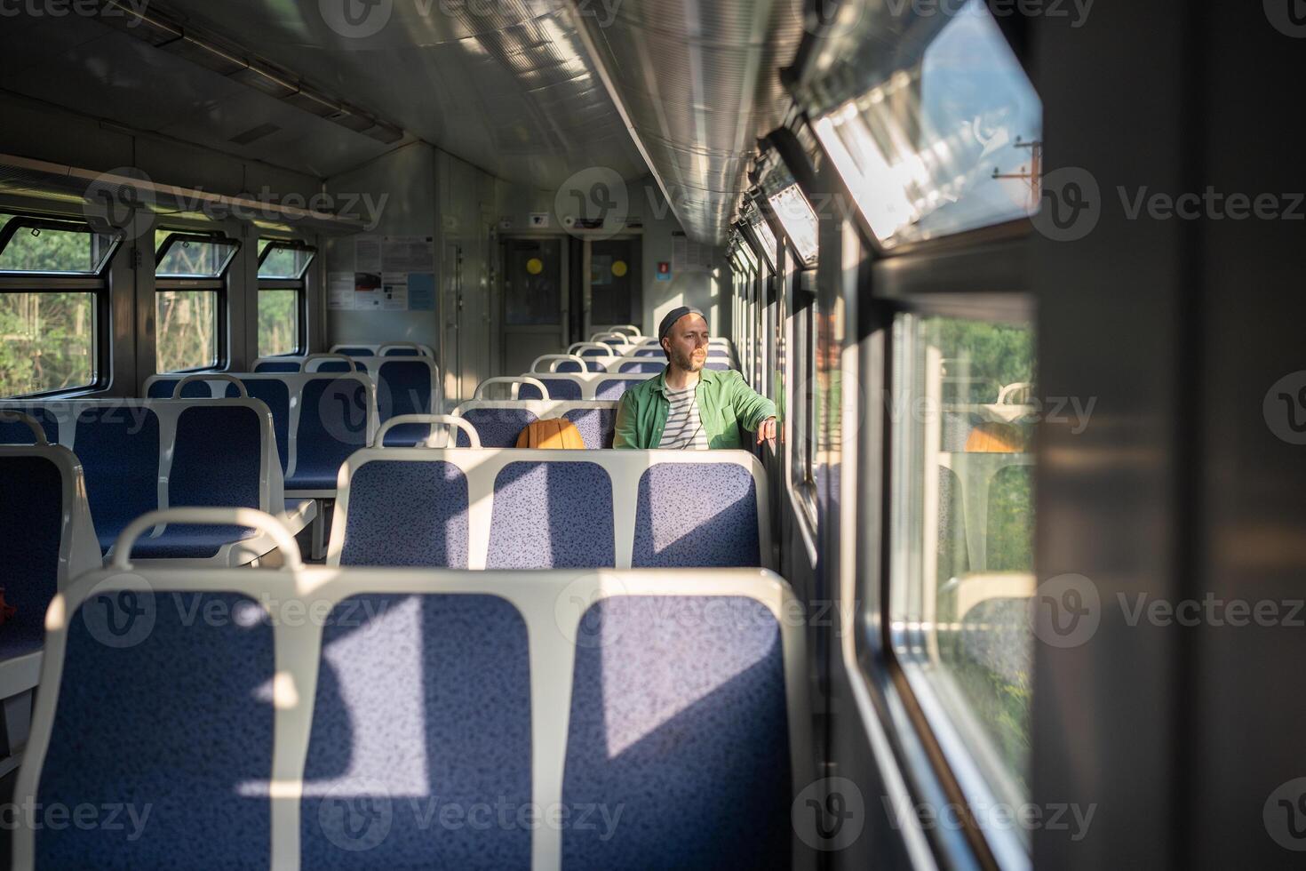 Pensive man with backpack travels solo on train. Urban travel at early hour, exploration and tourism photo