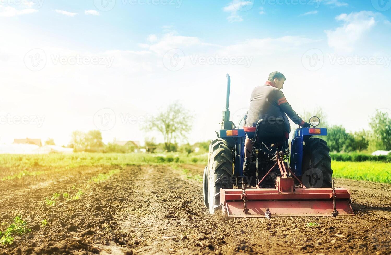 Farmer on a tractor with milling machine loosens, grinds and mixes soil. Cultivation technology equipment. Loosening the surface, cultivating the land for further planting. Farming and agriculture. photo