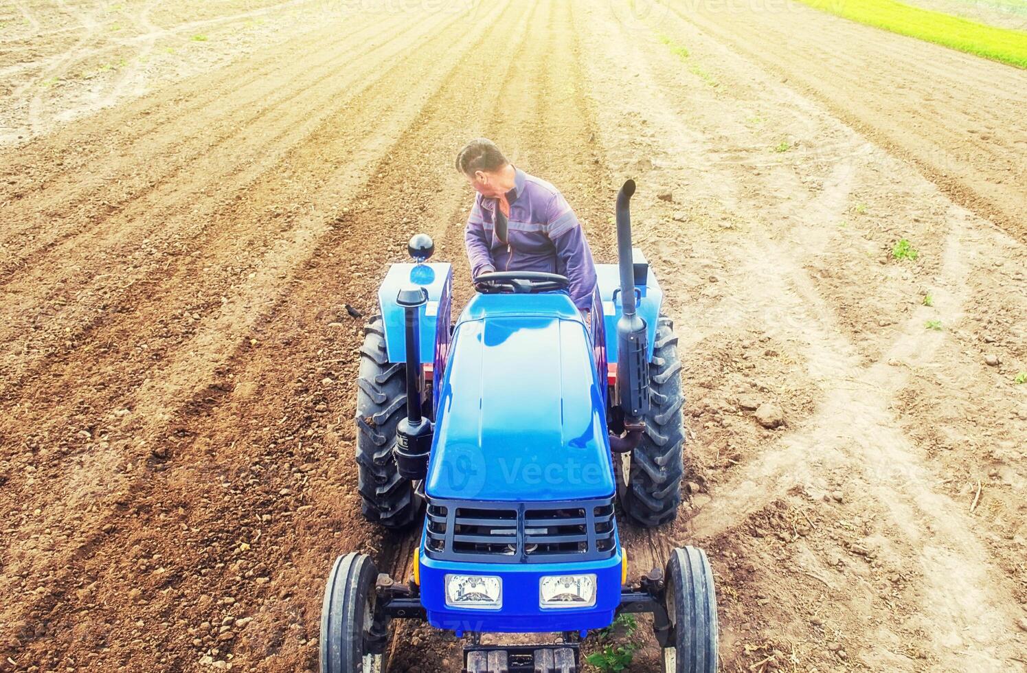 A farmer on a tractor cultivates a farm field. Soil milling, crumbling and mixing. Preparatory work for a new planting. Loosening surface, cultivating land for further planting. Agroindustry, farming. photo
