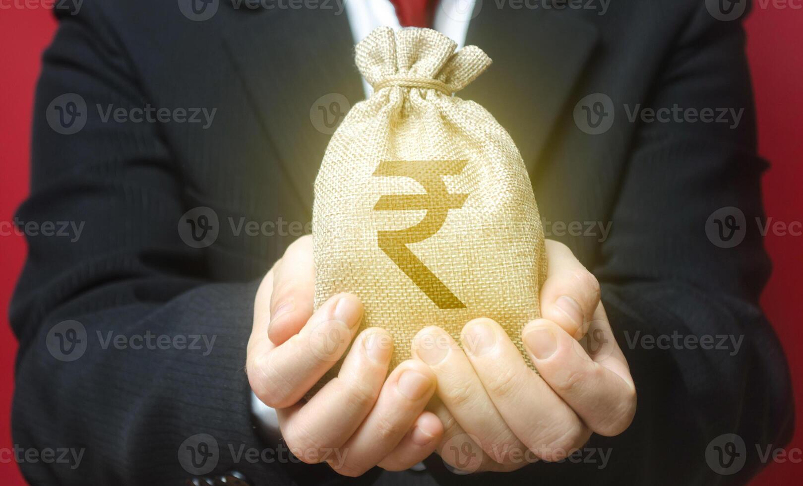 A man holds out a indian rupee money bag. Budget management, tax collection. Trade, economics. Granting financing business project or education. Provision cash financial loan credit. Bank deposit. photo