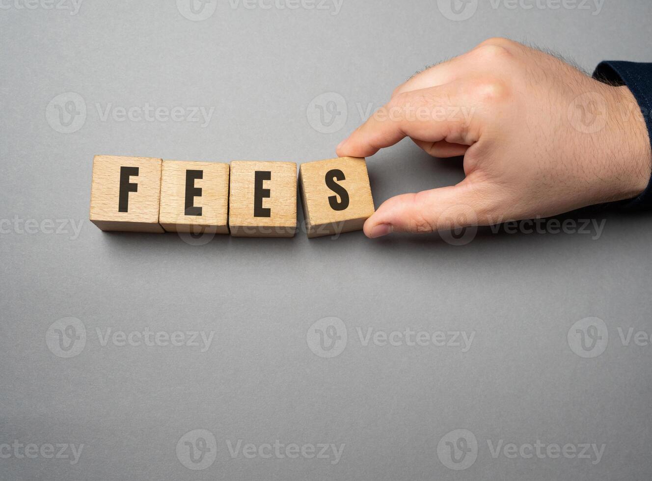 Fees word concept. Fixed price charged for a specific service. Business and finance concept. Costs, charges, commissions, penalties. Cost, fee and taxes. Wooden blocks photo