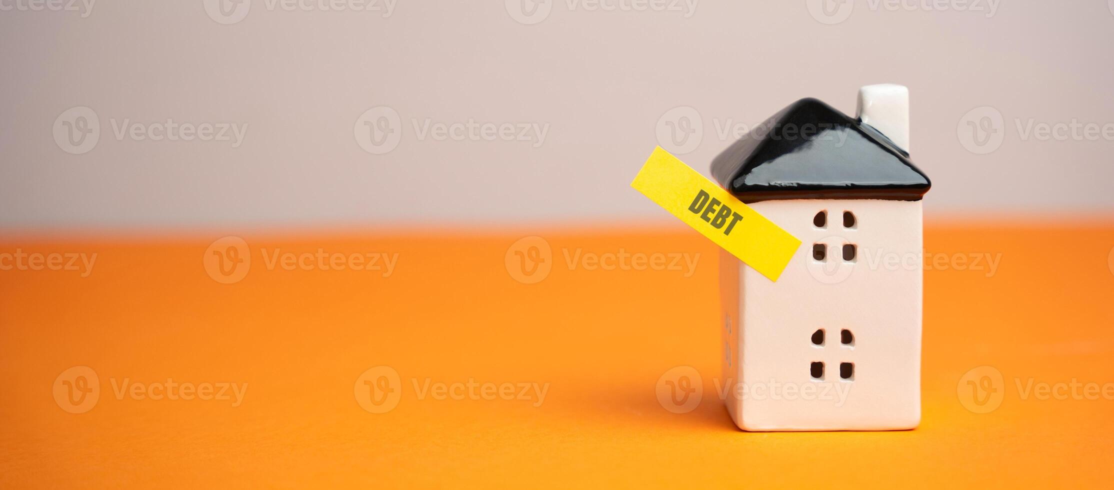 Miniature house with a note Debt. Reminder to pay taxes and rent. Paying off debts for housing and real estate. Copy space photo