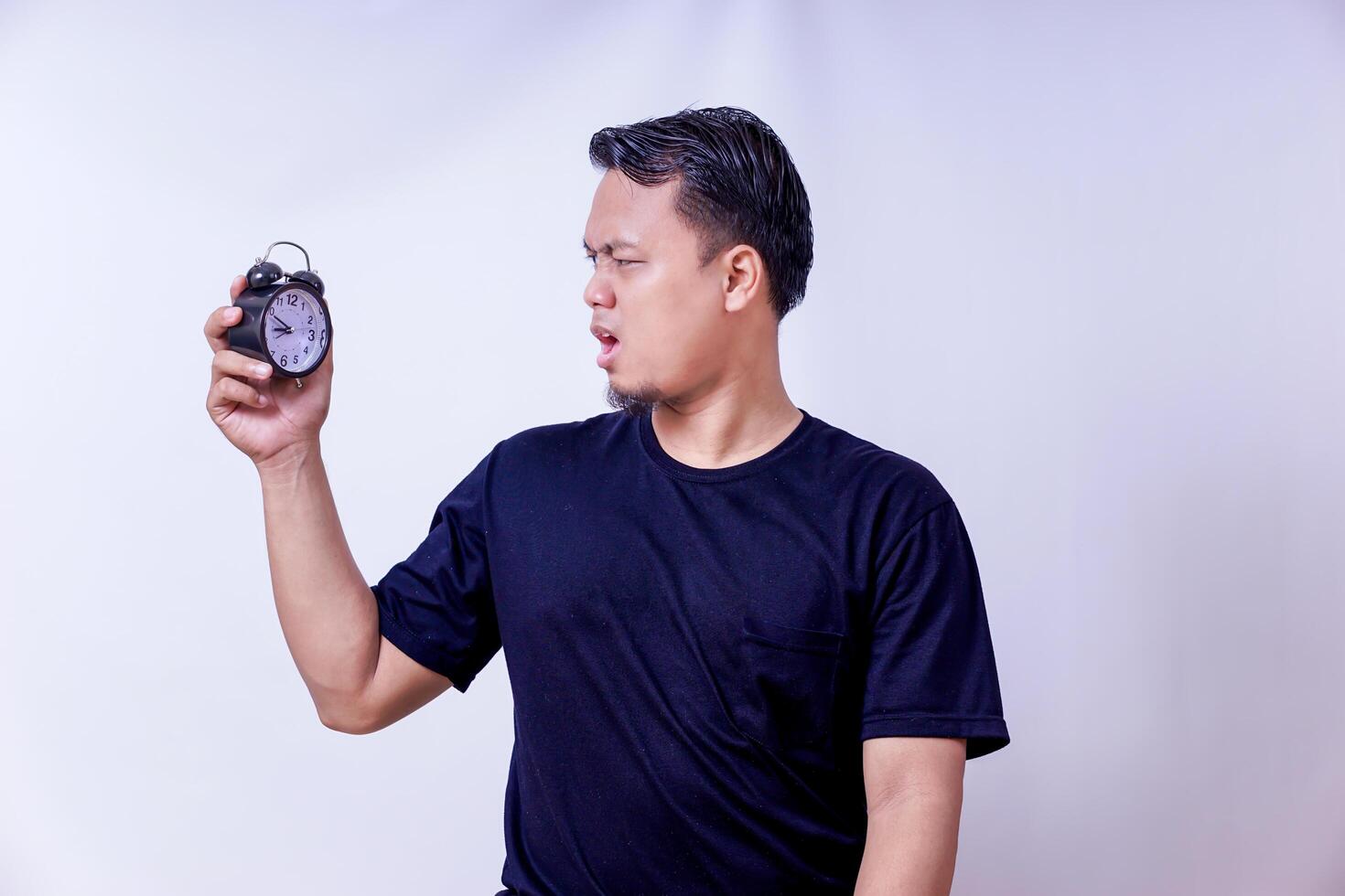 a man holding an alarm clock in his hand islolated on white photo