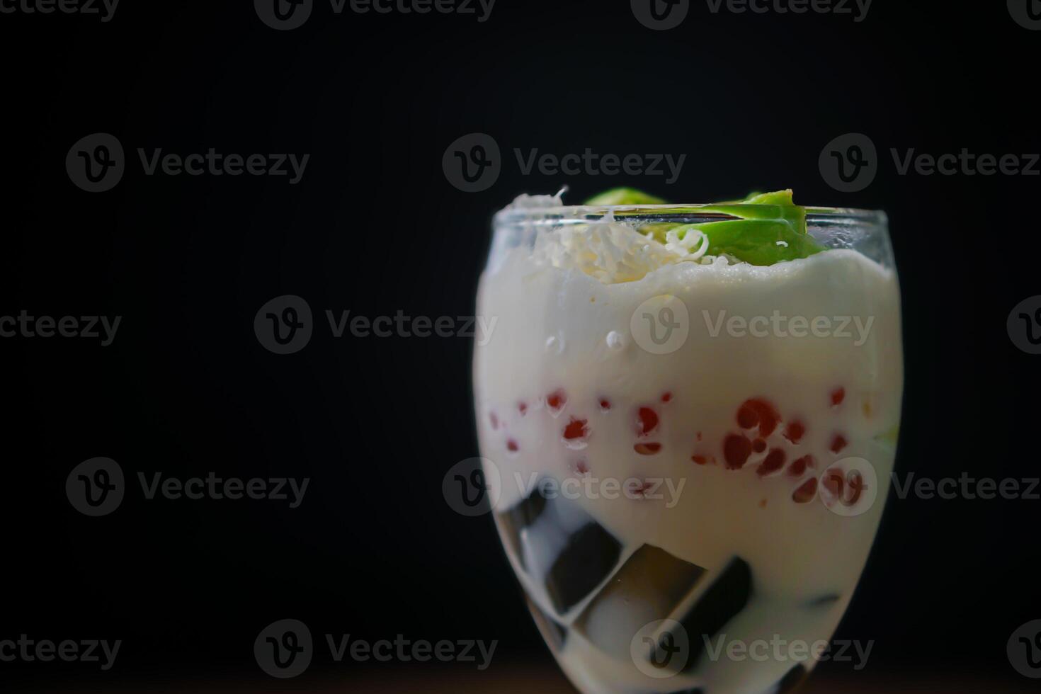 A close up refreshing dessert glass filled with creamy coconut and colorful tapioca pearls photo