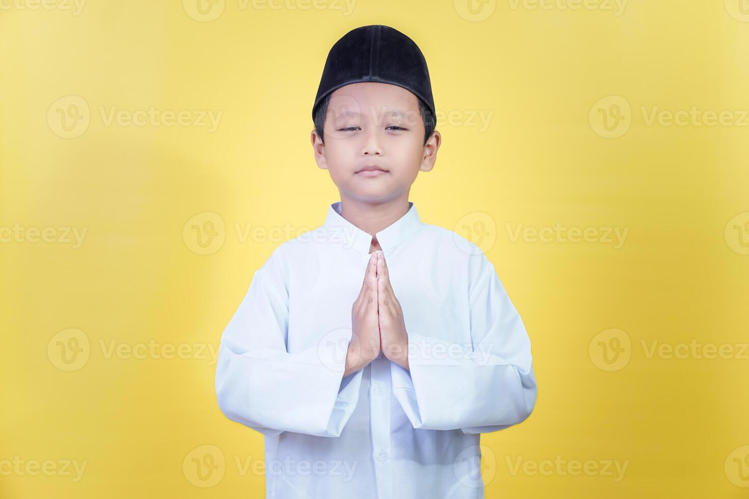 A young asian boy in traditional attire expresses joy and gratitude for Ramadan photo