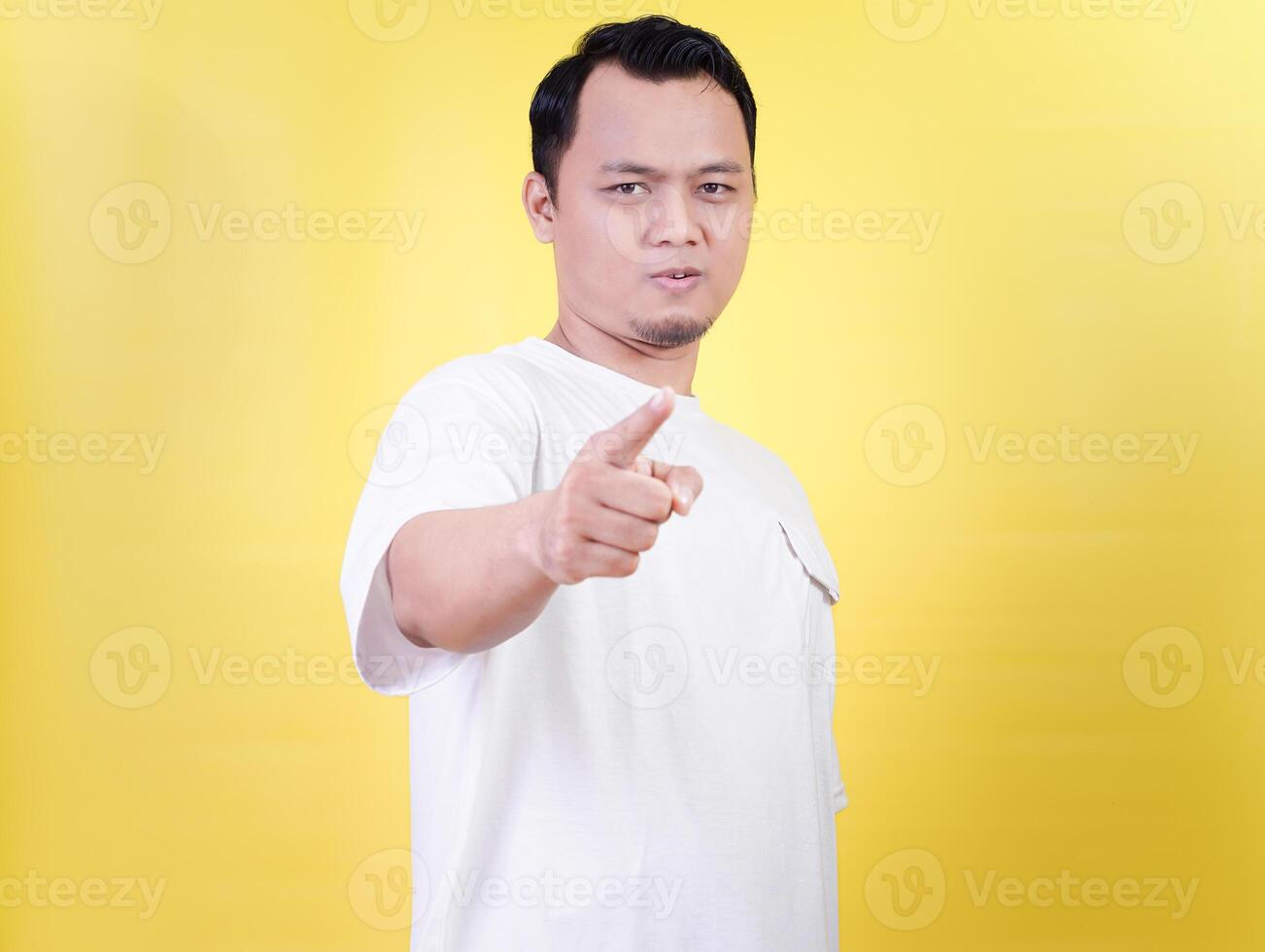 An asian man confidently points forward against a bright yellow background. photo