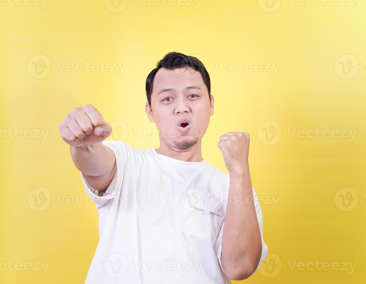 a man in a white shirt is making a fist isolated on yellow photo