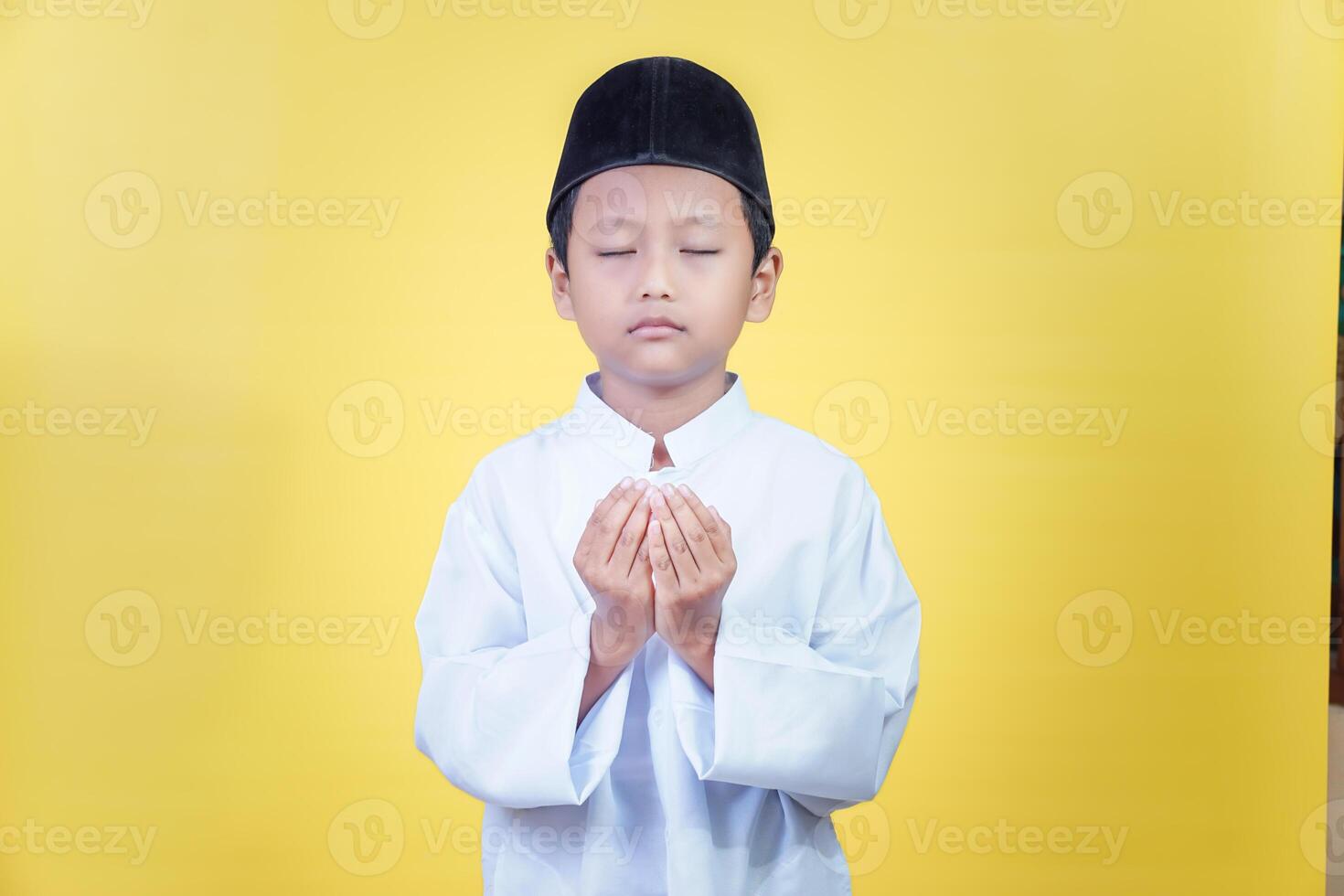 A young asian boy in prayer attire reflects the spirit of Ramadan Kareem with devotion photo