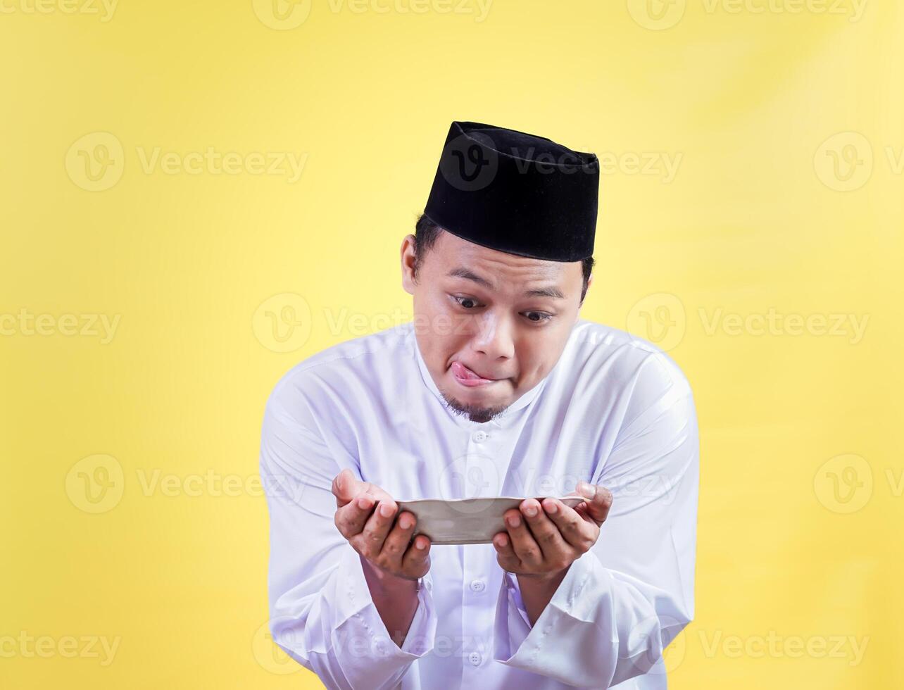 asian man in traditional attire looks hungrily at a plate photo