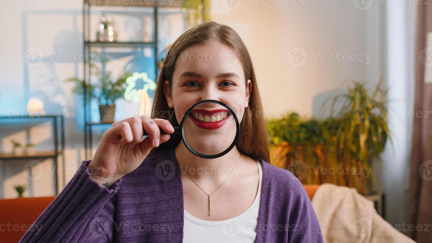 Woman holding magnifier glass on teeth, happy expression, showing funny smiling silly face mouth photo