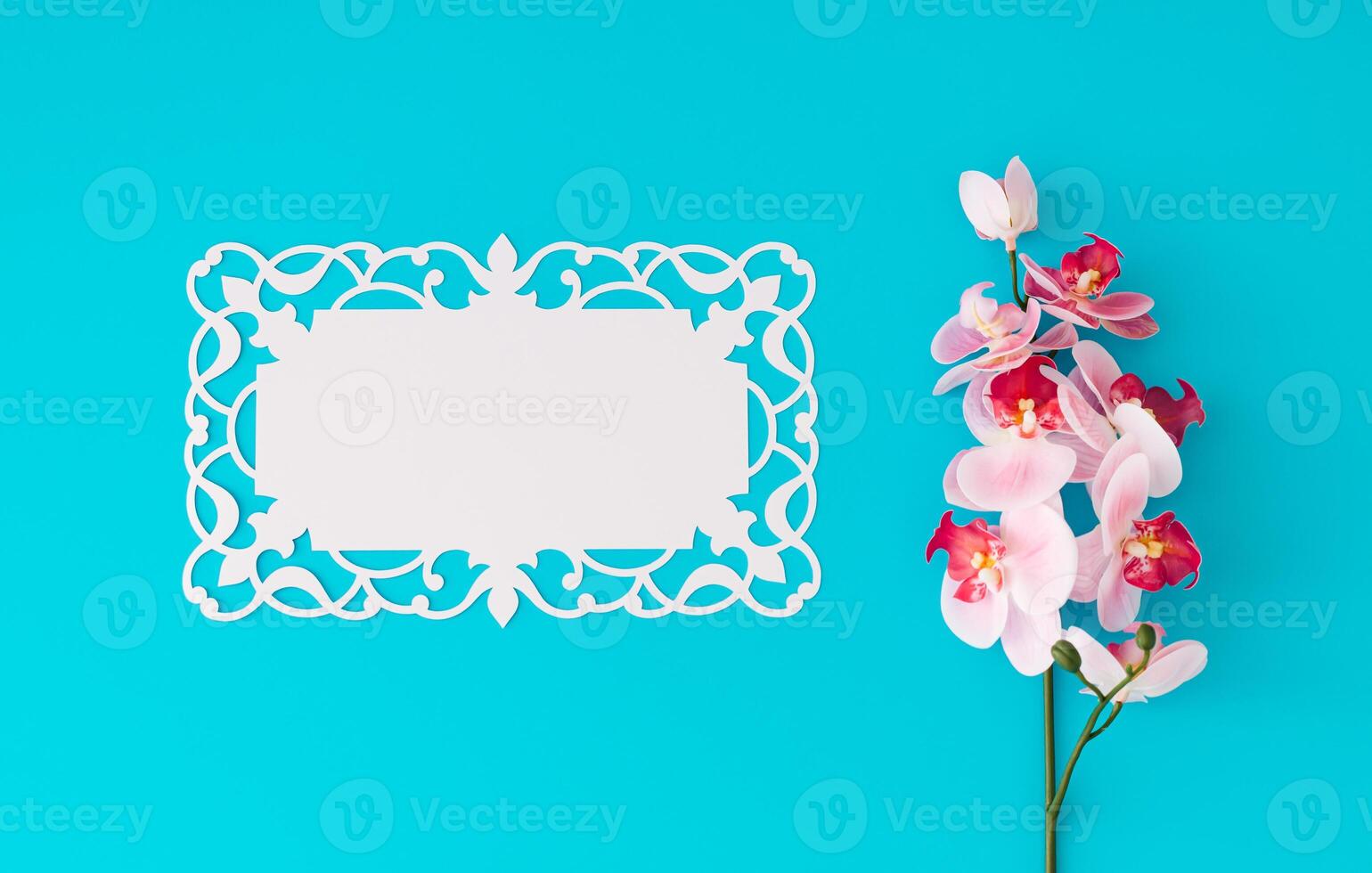 Beautiful orchid flower on light blue background with paper card note. Minimal concept. Creative spring and summer layout. Flower aesthetic with unique copy space. Flat lay, top of view. photo