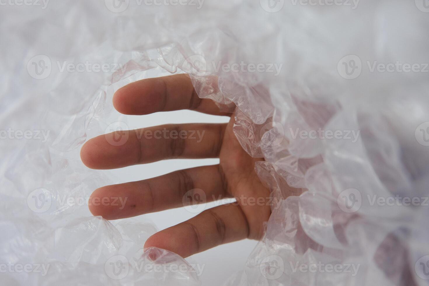 Hand Reaching Through Transparent Bubble Wrap, Symbolizing Exploration and Curiosity photo