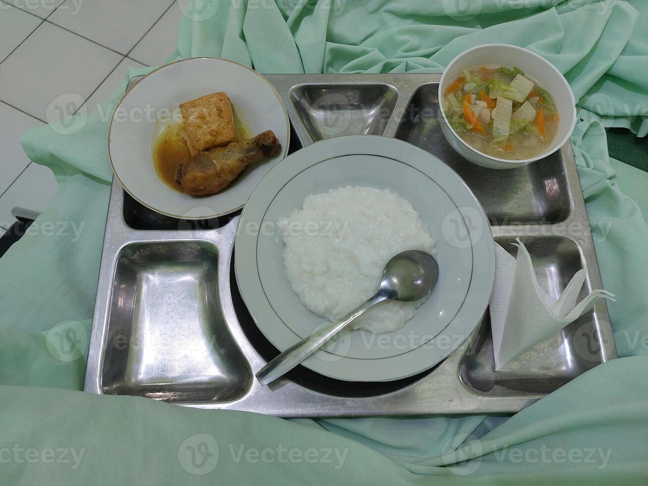 Hospital Meal on Tray Featuring Rice Porridge, Vegetables, and Chicken Dish photo
