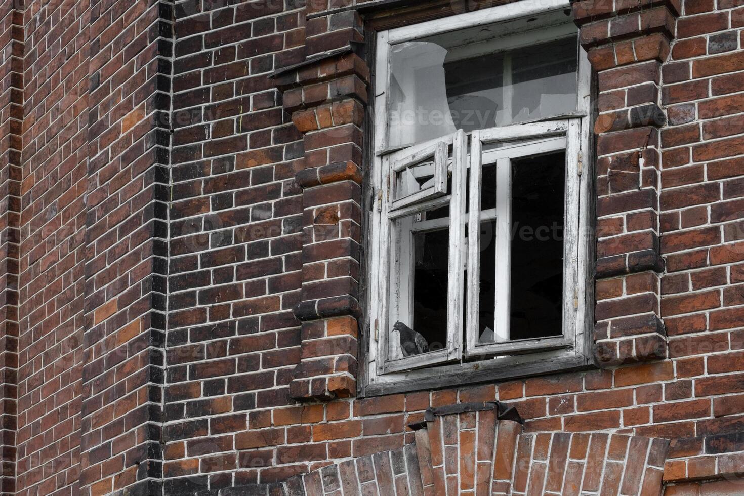 A fragment of a brick wall and a broken window of an old abandoned house. photo
