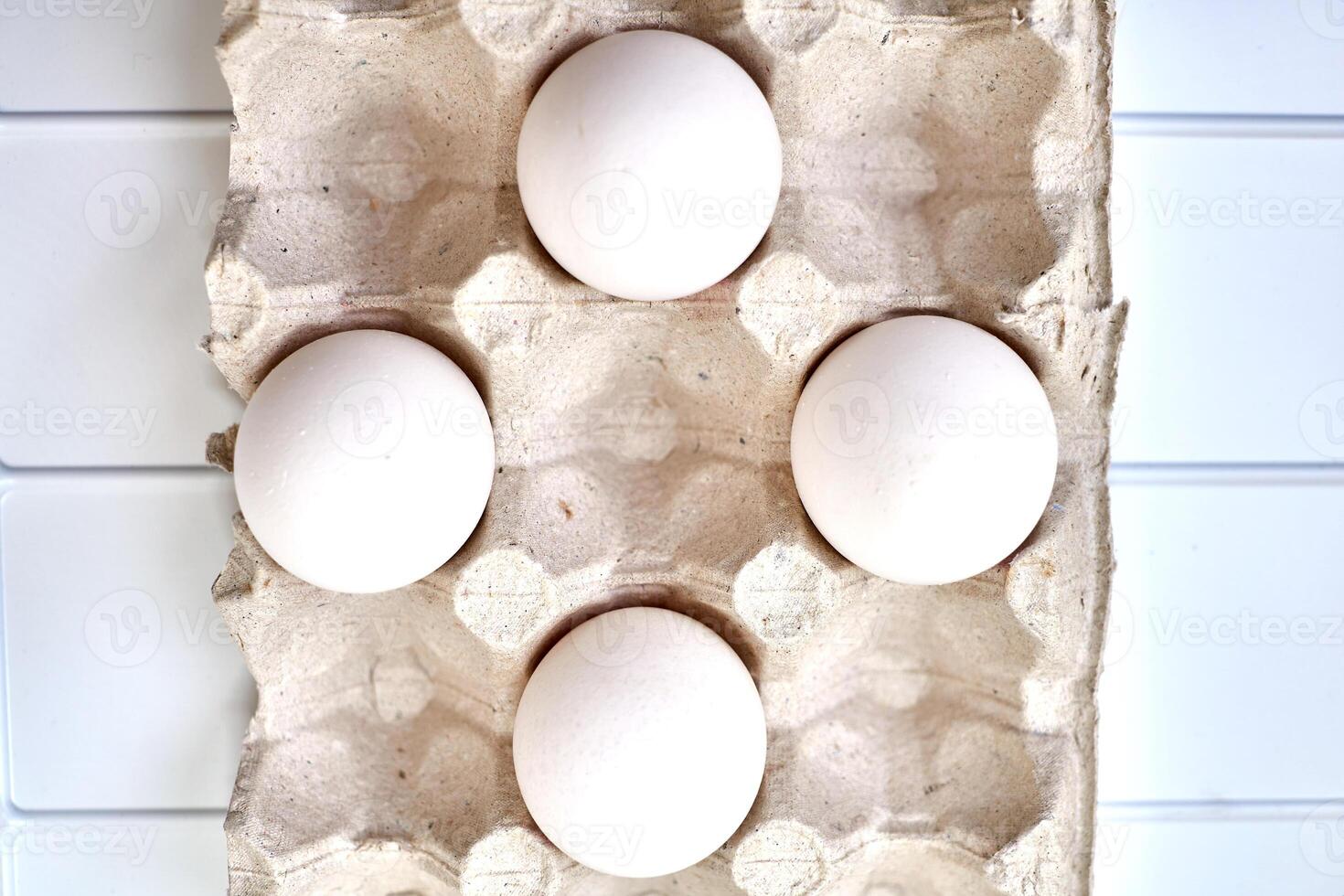 White eggs in a packing carton on a plastic surface photo