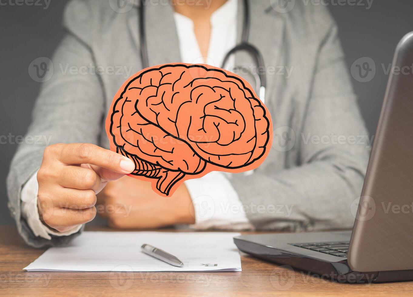 Doctor in a suit holding a brain symbol made from paper while sitting at the table in the hospital photo
